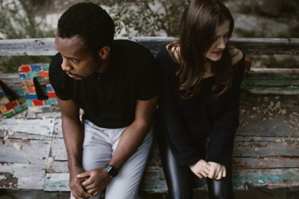 couple separated seating on a bench