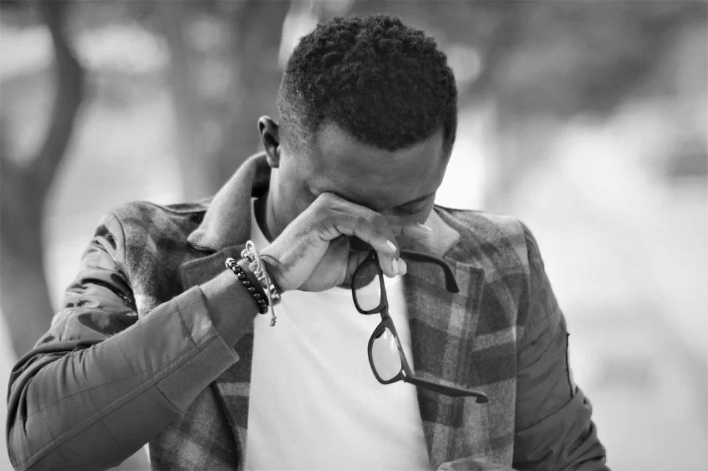 man crying holding his glasses